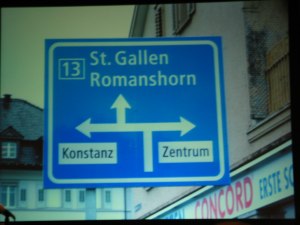 Blue highway sign with three arrows and various type treatments in Frutiger